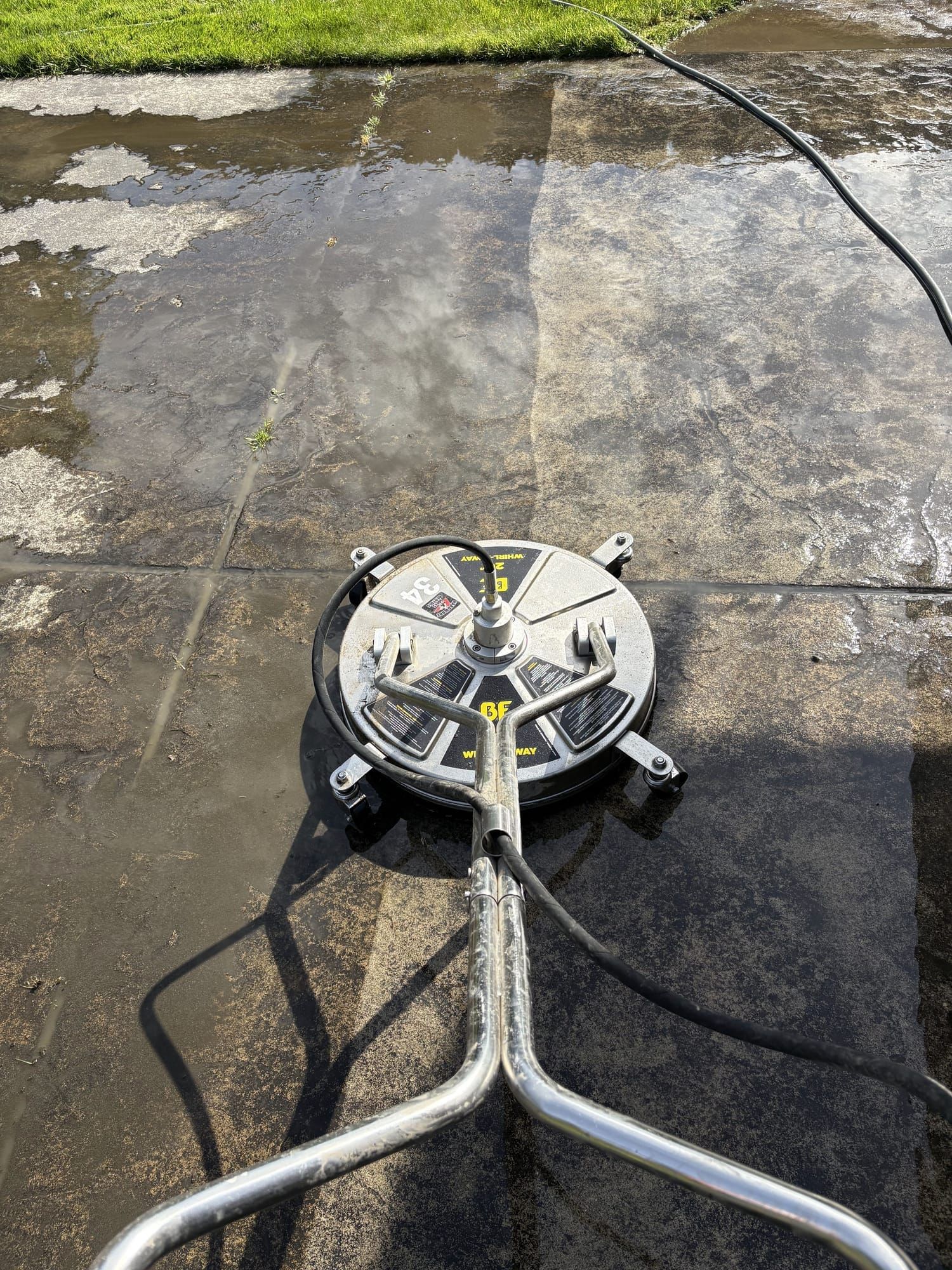 Surface cleaner attachment in use on a concrete driveway